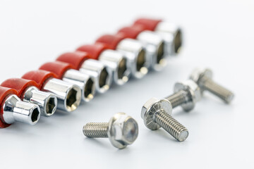 Chrome socket wrench heads with red holders arranged beside three metal bolts on a clean white surface for mechanical projects.