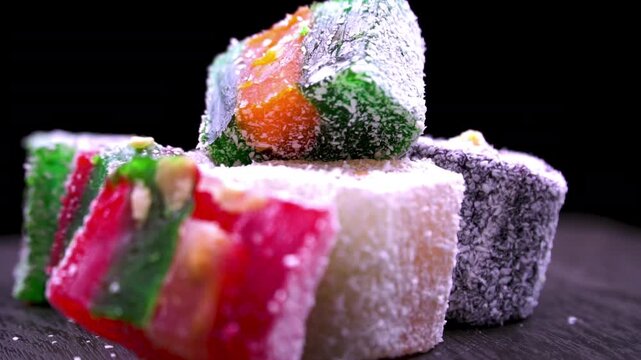 Assorted Turkish Delight (Rahat Lokum) cubes with coconut flakes and nuts, macro traditional eastern sweet dessert on black.