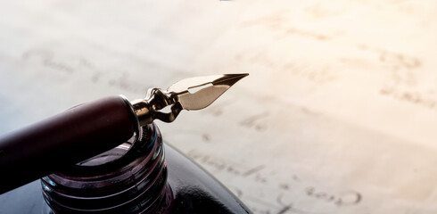 Fountain pen on an antique inkwell. Vintage nib pen and handwritten. Old history background. Retro...
