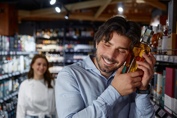 A man is smelling a bottle of perfume inside a store