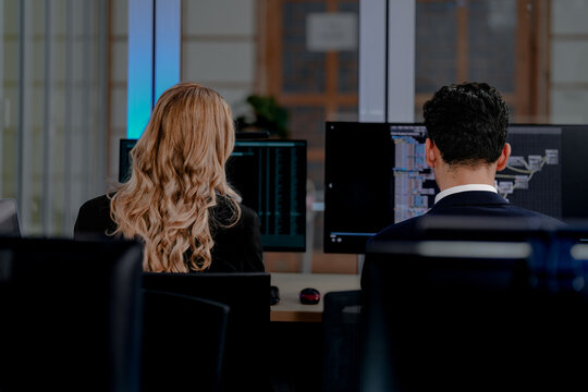 Intense coding workflow: Two software developers deeply focused on programming complex algorithms, side-by-side on dual monitors. A glimpse into modern software engineering life.