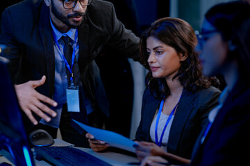 Future AI control center. Diverse oversight team monitors autonomous system performance. Analyzing real time execution logs and data streams displayed on advanced computer screens late night.