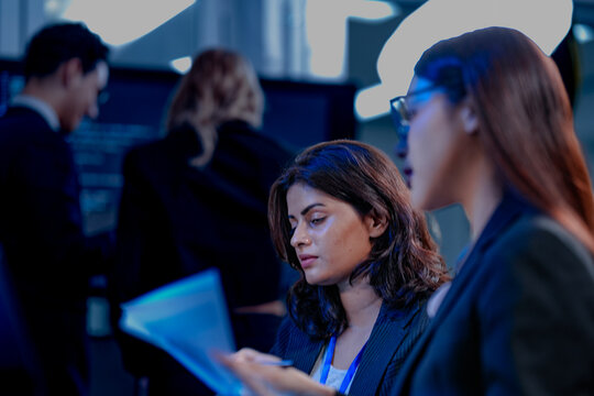 Intense collaboration hub. Diverse AI team deep dive into project data late night. Manager guides Asian colleagues reviewing analytics for a new service launch in tech office.