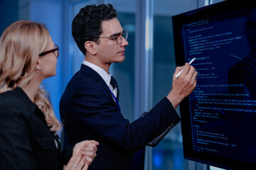 Code breakthrough achieved. Smiling senior developer points to a successful code segment on screen,...