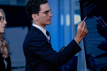 Code breakthrough achieved. Smiling senior developer points to a successful code segment on screen,...