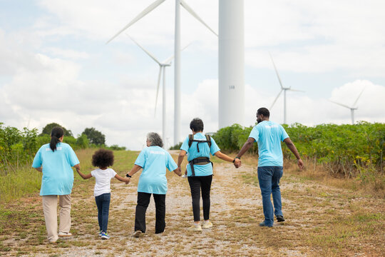 back view Volunteers are walking behind a windmill farm, volunteer charity people. charity community service event, ngo business and outreach, Group Diverse people meeting at park for donation