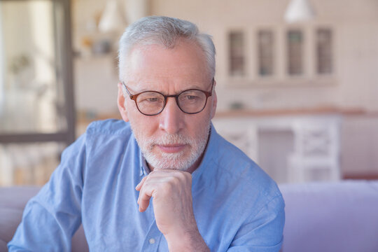 Serious pensive thoughtful caucasian old senior elderly man grandfather thinking about his grandchildren, left alone at home. Health problems, paying bills concept - Powered by Adobe