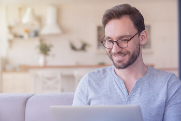 Successful confident young adult businessman using laptop for checking e-mail, searching web,...