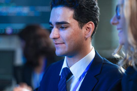 A focused young businessman in a suit interacts intently with his digital tablet late at night analyzing project data in a modern high tech office work environment. - Powered by Adobe