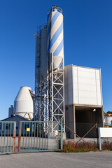 Tall tanks with blue and white stripes rises beside a metal framework