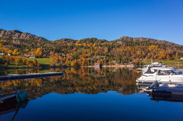A tranquil autumn seaside scene with colorful trees along the shore, Norway