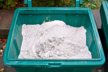 Salt prepared for winter road, pathway maintenance. Closeup view of granular salt mixture stored in green winter maintenance container used for treating icy sidewalks and enhancing pedestrian safety