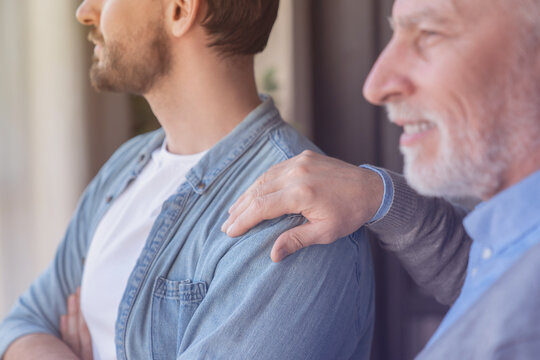 Close up shot of a caucasian old elderly senior man supporting his young adult son looking at the window in future together at home. Happy father`s day! I love you, dad! - Powered by Adobe