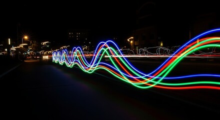 Abstract light trails of blue red and green waves across a dark city street at night image