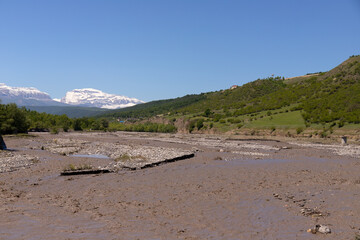 A muddy river in a canyon in the mountains.