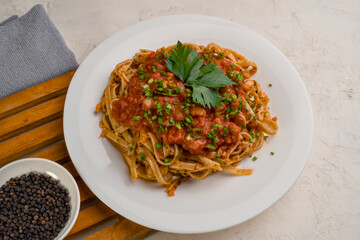 a plate of pasta noodles topped with tomato sauce mixed with meat, cheese, spices, onions and lettuce