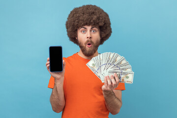 Man holding fan of banknotes and smart phone with empty screen for advertisement.