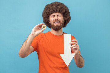 Crying upset sad man showing white arrow pointing down and bitcoin, downgrade.