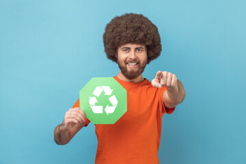 Man holding waste recycling symbol in his hand, worrying about ecology, pointing finger to camera.
