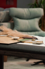 A display of ceramic tile samples in various neutral tones arranged in a showroom. The collection includes stone-texture and matte-finish tiles, creating a professional interior design workspace setti