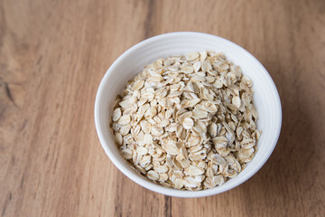 Bowl of Dry Rolled Oats on Wooden Table