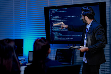 Fototapeta premium A focused male AI solutions architect in a futuristic control hub debates generative AI applications collaborating on a complex machine learning model with his team under atmospheric blue lighting.