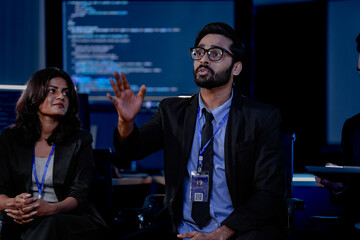 A large, diverse team of business professionals in a group meeting. An Indian man with a tablet...