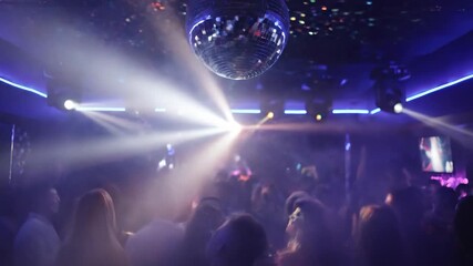 A party scene with a disco ball reflecting lights and people in a crowd - Powered by Adobe