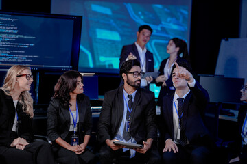 A large, diverse team of business professionals in a group meeting. An Indian man with a tablet...