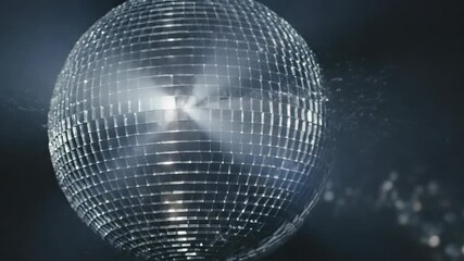 A close-up image of a disco ball, a perfect sphere of mirrors. Light refracts and scatters in beams across the backdrop
