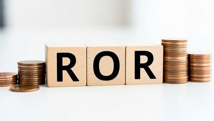 Wooden blocks spelling ror with coin stacks on a white surface representing financial concepts idea 100