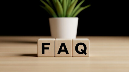 Faq spelled out in wooden blocks with a plant in the background on a light brown surface view from front