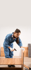 Concept of Furniture assembly service. Assembling new shelves and cabinet. Woman in workwear...