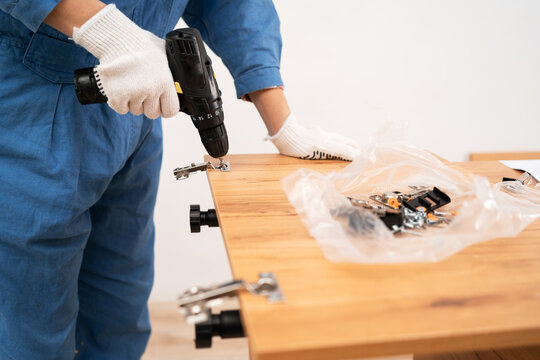 Female worker Installing a furniture door hinge, close-up. Furniture assembling
