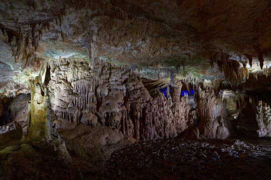 Spectacular stalactite formations in illuminated underground show cave chamber