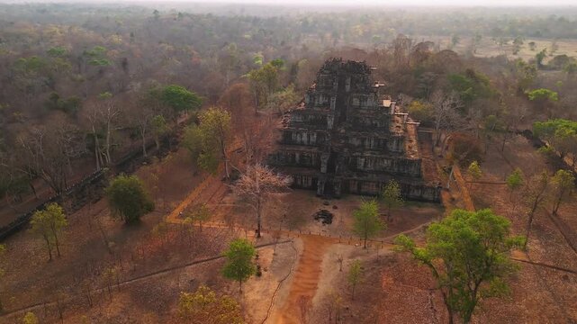 Aerial view of the koh ker temple, a seven tiered pyramid standing amidst the dry cambodian jungle during a hazy morning light.