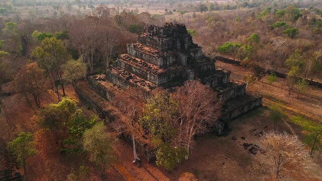 Aerial view of the koh ker temple, a seven tiered pyramid standing amidst the dry cambodian jungle during a hazy morning light.
