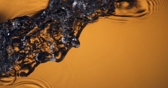 Golden Water Stream Pouring Down In Slow Motion Creating Ripples And Fluid Shapes With Warm Reflections And Cinematic Texture at 1000 fps.