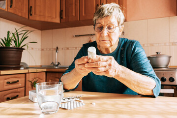 An elderly woman carefully reads the instructions on a bottle of medication. Age-related medication...