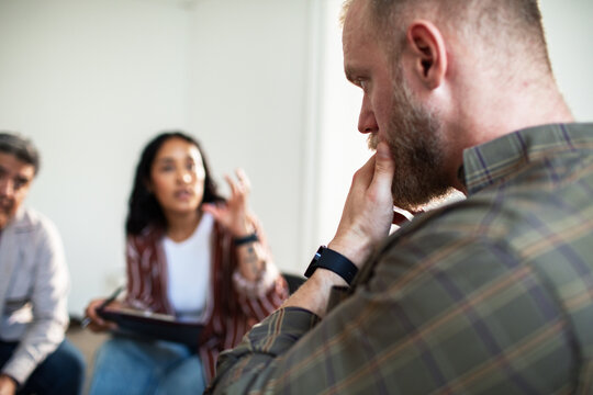 Adult man listening thoughtfully during group therapy indoors