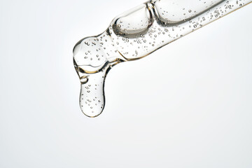 Cosmetic pipette dripping clear serum fluid with bubbles