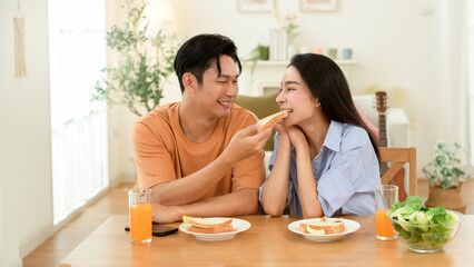 Couple Enjoying Breakfast With Fresh Juice and Sandwiches in a Bright Kitchen Setting
