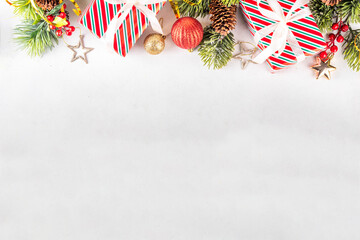 Fototapeta premium White background with Christmas and New Year festive border contains gift boxes, Christmas fir tree branches, decorations and holiday baubles