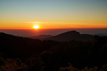 Beautiful sunrise scenery over lush green valleys and a clear sky in Chiang Mai, Thailand.