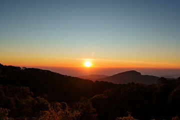 Beautiful sunrise scenery over lush green valleys and a clear sky in Chiang Mai, Thailand.