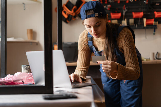 Female craft shop owner using laptop and credit card for secure online purchases and e-commerce