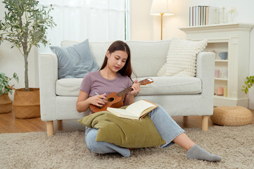 Obraz premium Young Asian Artist Writing Music in Cozy Living Room Surrounded by Plants and Natural Light