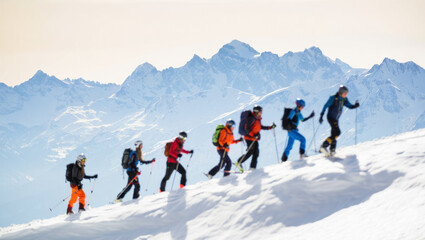 A group of skiers equipped with backpacks and poles moves in a line across a bright snowy ridge with vast sunlit mountain peaks rising sharply in the background