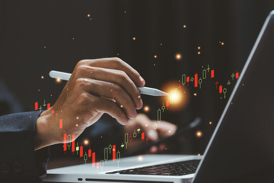A business professional analyzing financial data with a digital stylus, reviewing rising stock market charts on a laptop. Perfect for concepts of trading, investment strategy, fintech.