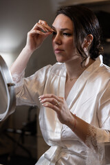Personal and intimate moment of a beautiful, elegant woman applying makeup.